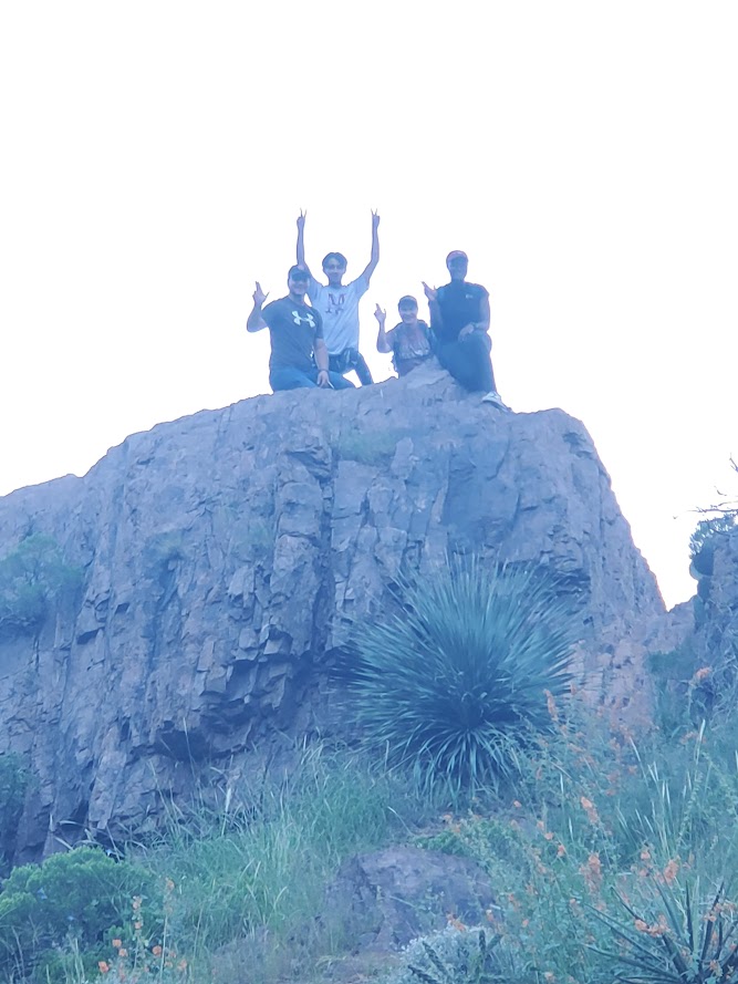 Members of Men of Color pose on top of a rock on a hike in Las Cruces, NM